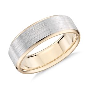 A wedding band that has a white inlay band with a yellow gold outside.